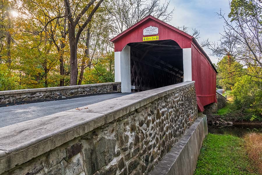 About Our Agency - Closeup View of a Red Covered Bridge Road in Bucks County Pennsylvania on a Sunny Day