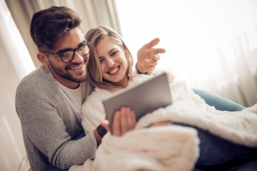Blog - Cheerful Young Married Couple Sitting Together at Home Using a Tablet
